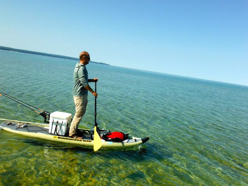 man paddleboarding in ocean fishing