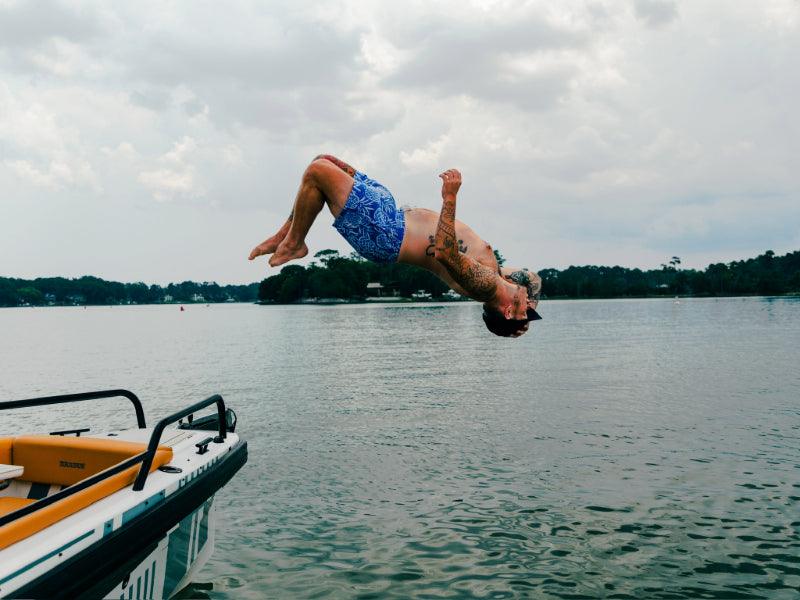 man backflipping off charter boat into water